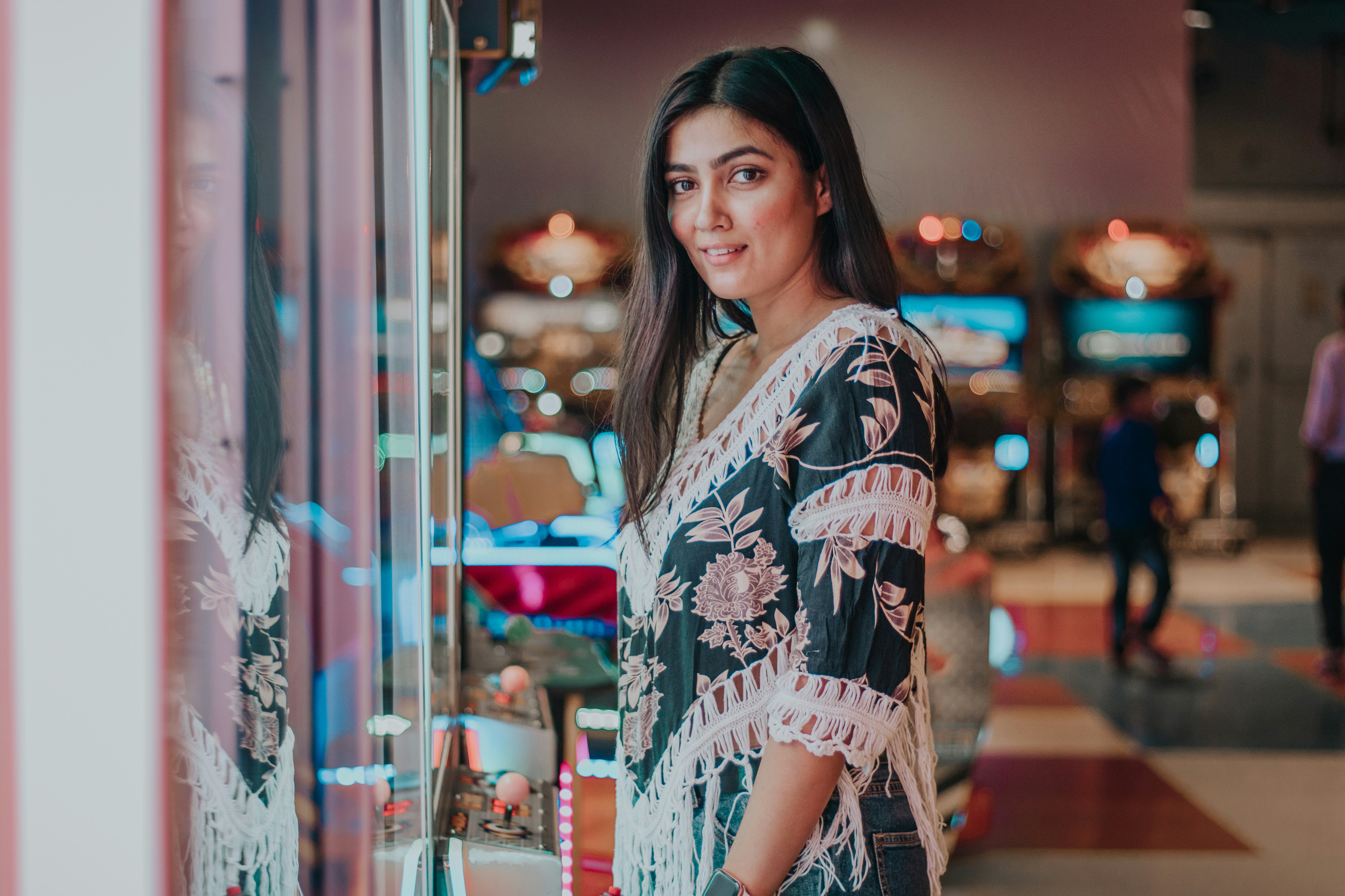 woman in white and blue floral long sleeve shirt standing near glass window